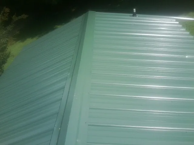 New green metal panels meeting at the ridge of a roof — Flat Roof Repair work by our crew in Bantry