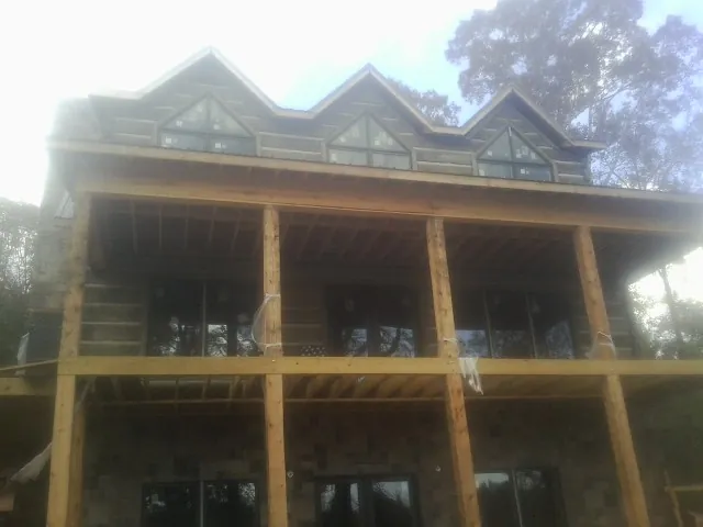 Dormers and porch framing on a large log home under construction — Roof Coating work by our crew in Bantry