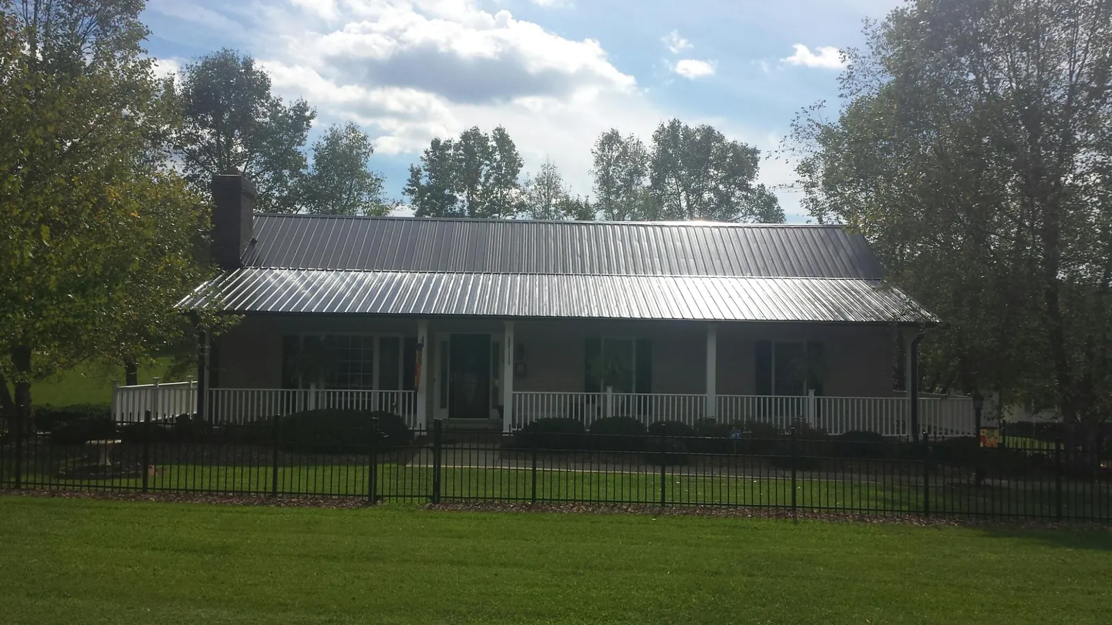 Gray metal roof on a brick ranch with a full width front porch — Gutter Guard Installation work by our crew in Bantry