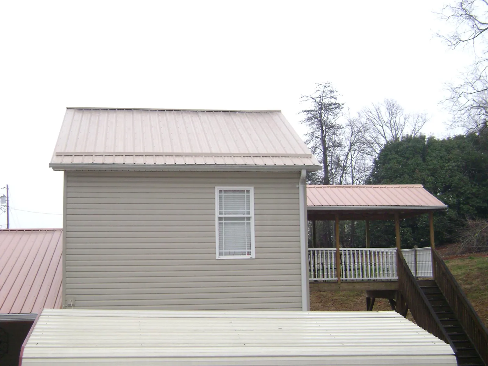 Tan metal roofs on a two story addition and attached porch, from a Roof Replacement job in Bantry