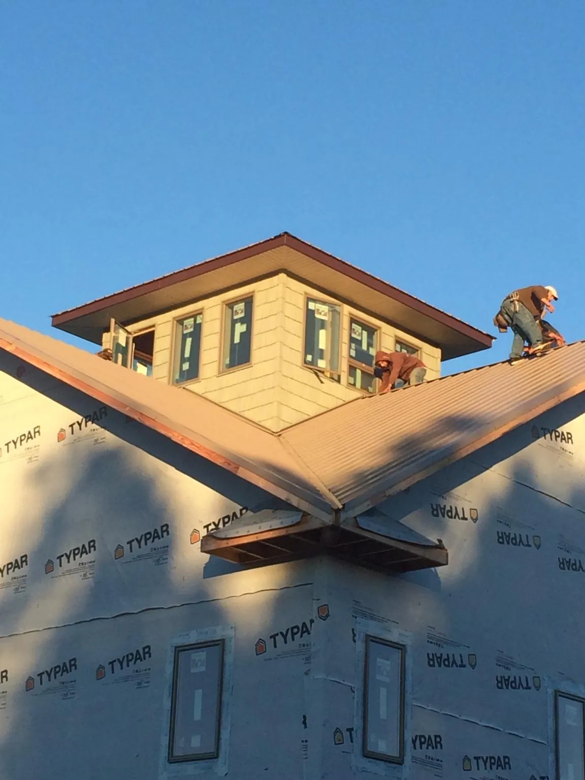 Roofers working around a rooftop cupola on a new metal roof at sunset — Roof Waterproofing in Bantry by Roofing Brothers